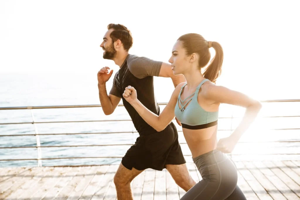 Fitness couple running on bridge side | South Ogden, UT | Timeless Skin and Wellness